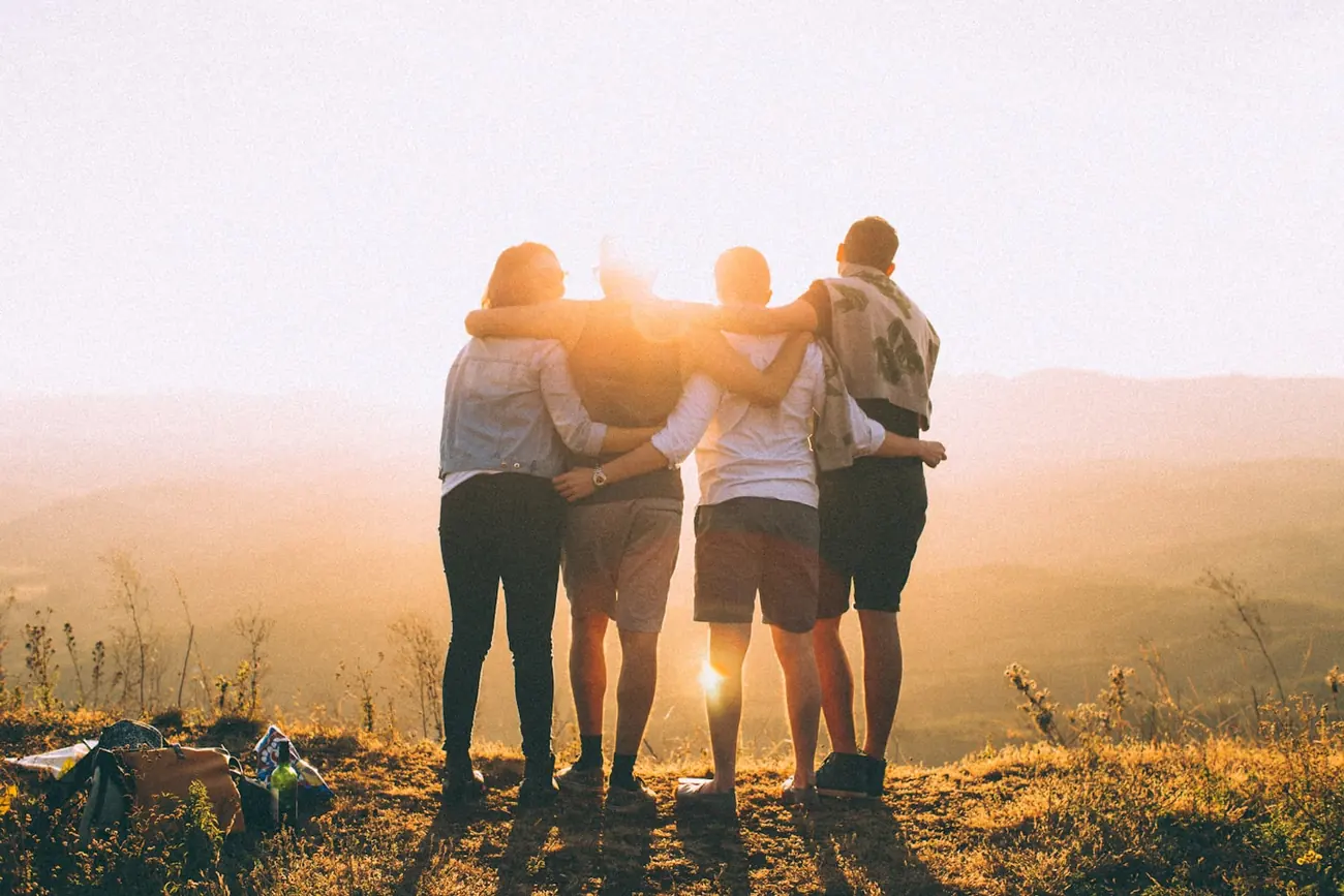 Un grupo de amigos abrazados mirando el atardecer